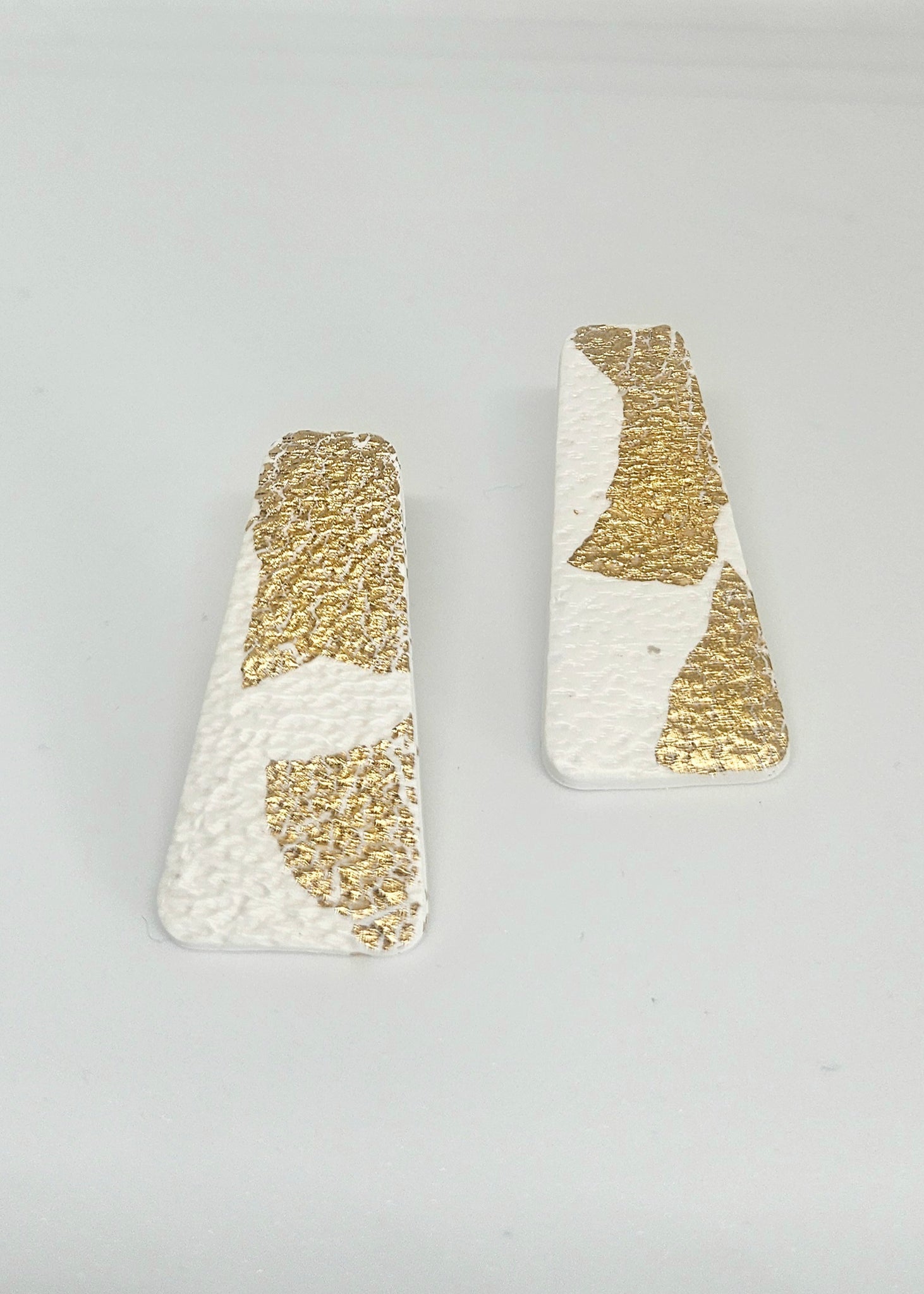 Pair of gold and white handmade polymer clay earrings  on a light gray background